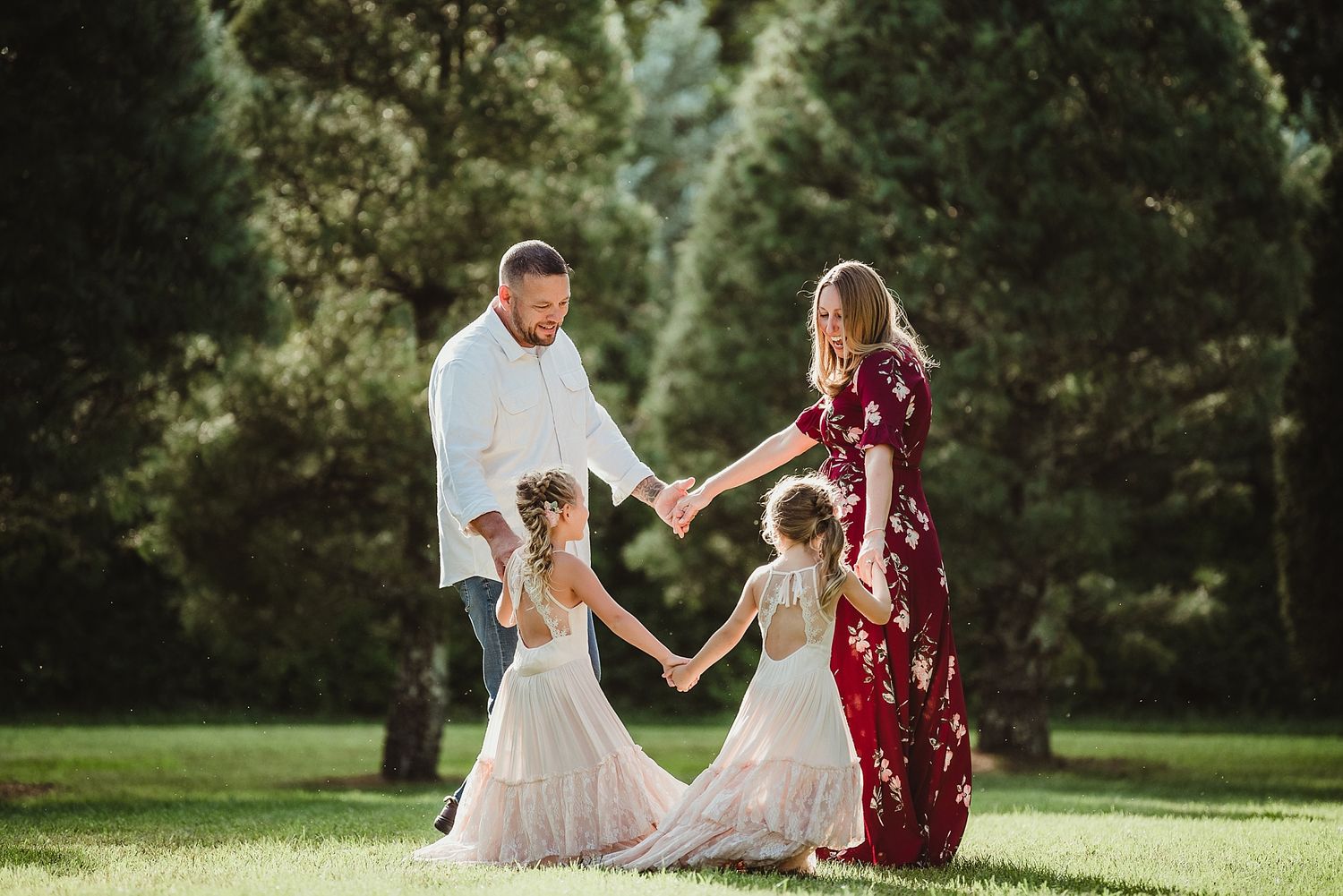 A family holds hands in a circle on green grass during golden hour.