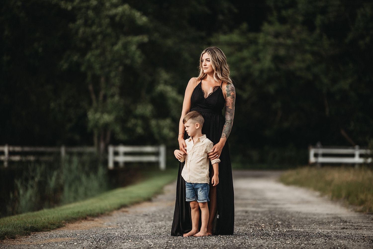 A parent and child share a tender moment together on a rustic path with white fences.
