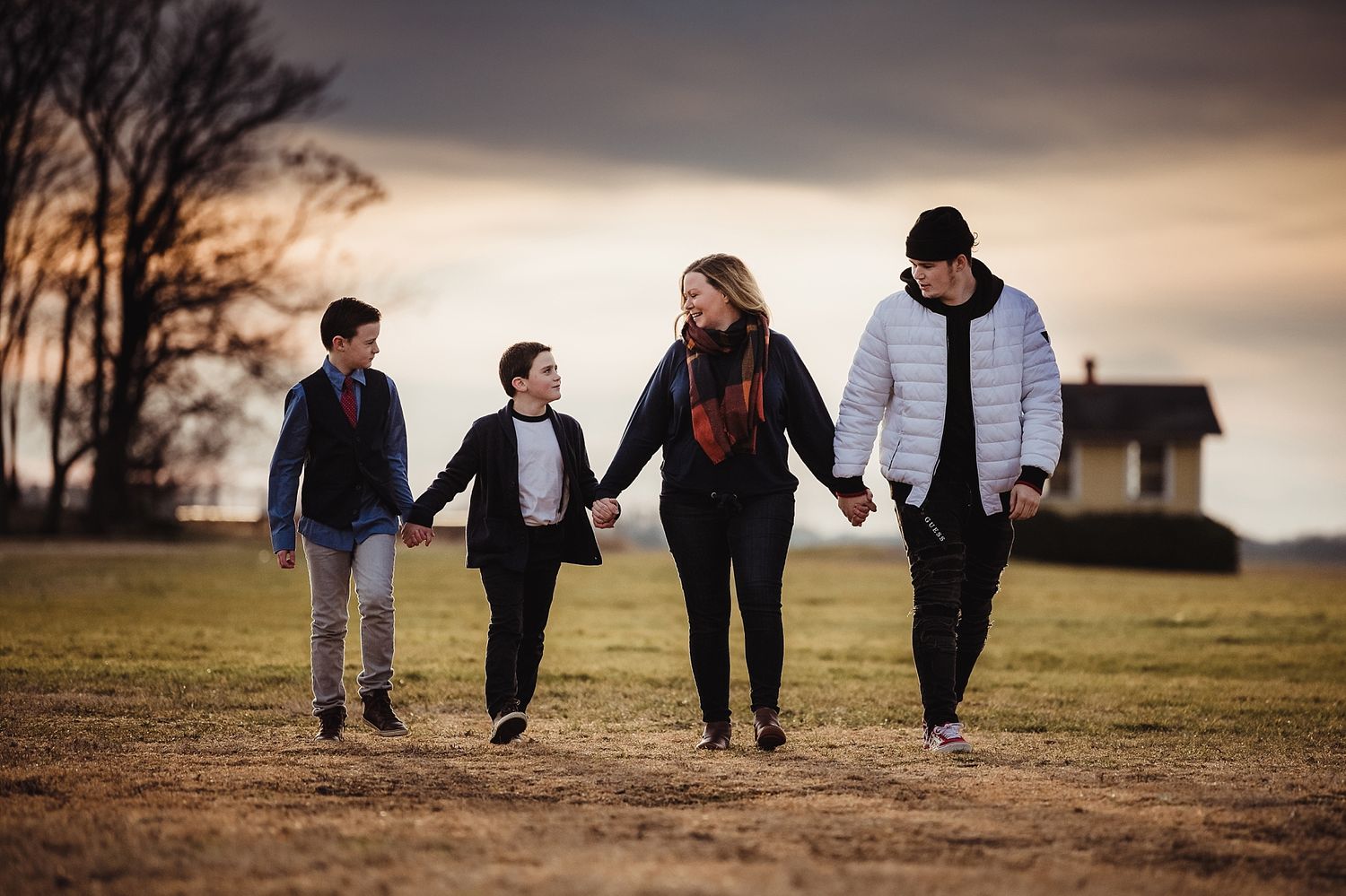 A family walking together hand in hand at sunset against a dramatic sky.