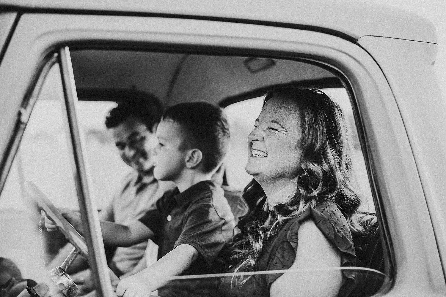 Black and white photo of joyful passengers enjoying a car ride together.