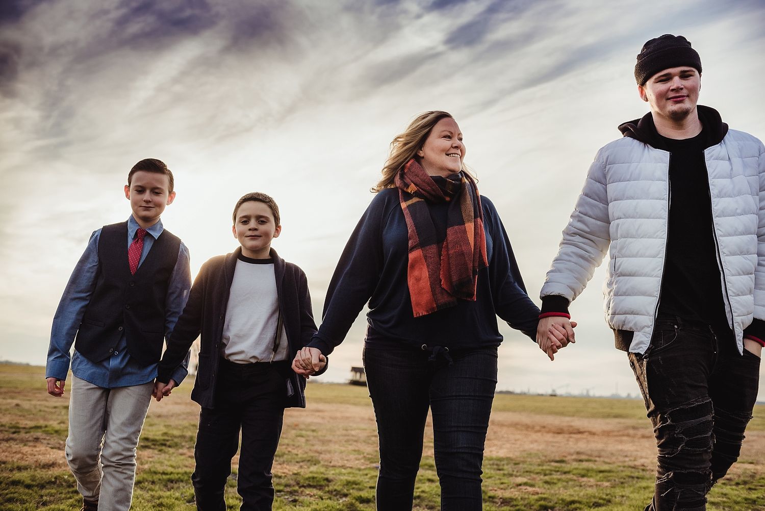 Family holding hands while walking together against dramatic cloudy sky.