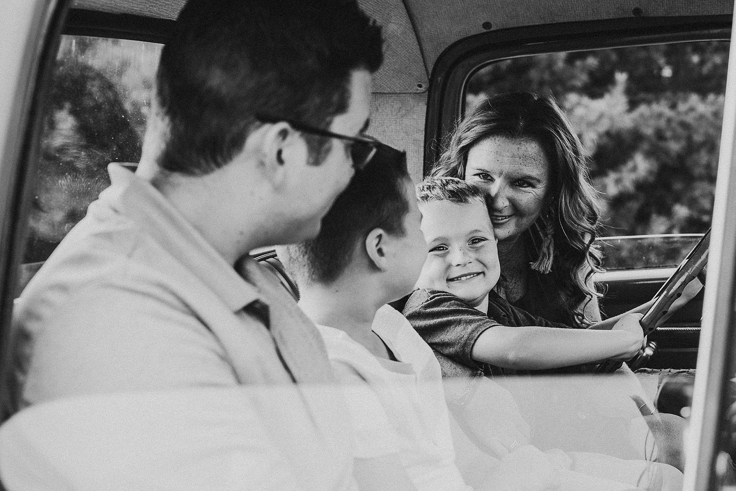 Black and white candid moment of joy captured inside vintage car.
