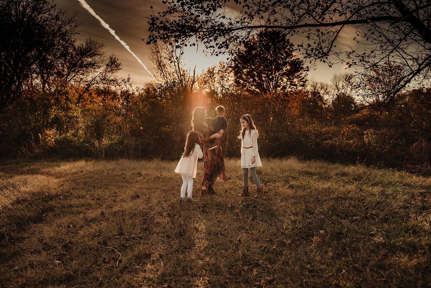 Golden sunset portrait in autumn field with lens flare effect.