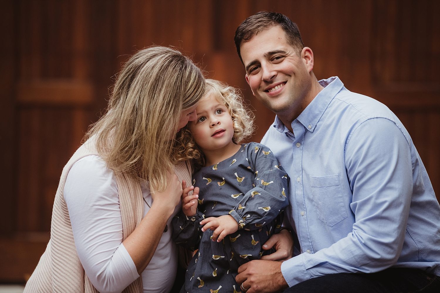 Casual family portrait session against wooden door background.