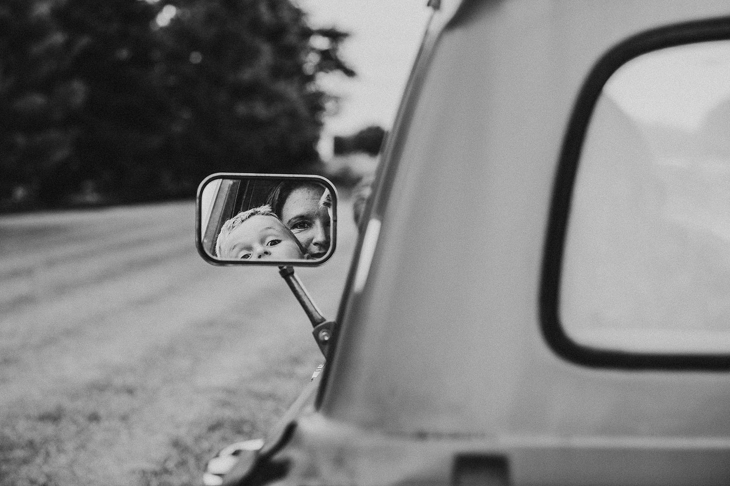 Black and white car mirror reflection shot on country road.