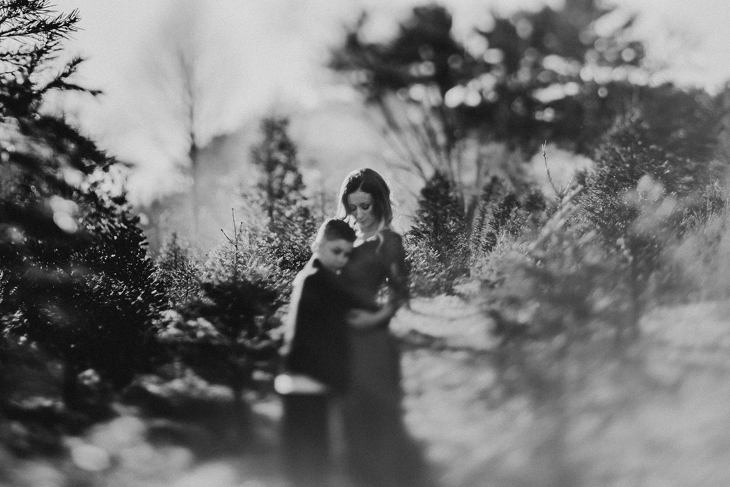 A dreamy black and white portrait captured through misty foliage in a forest setting.