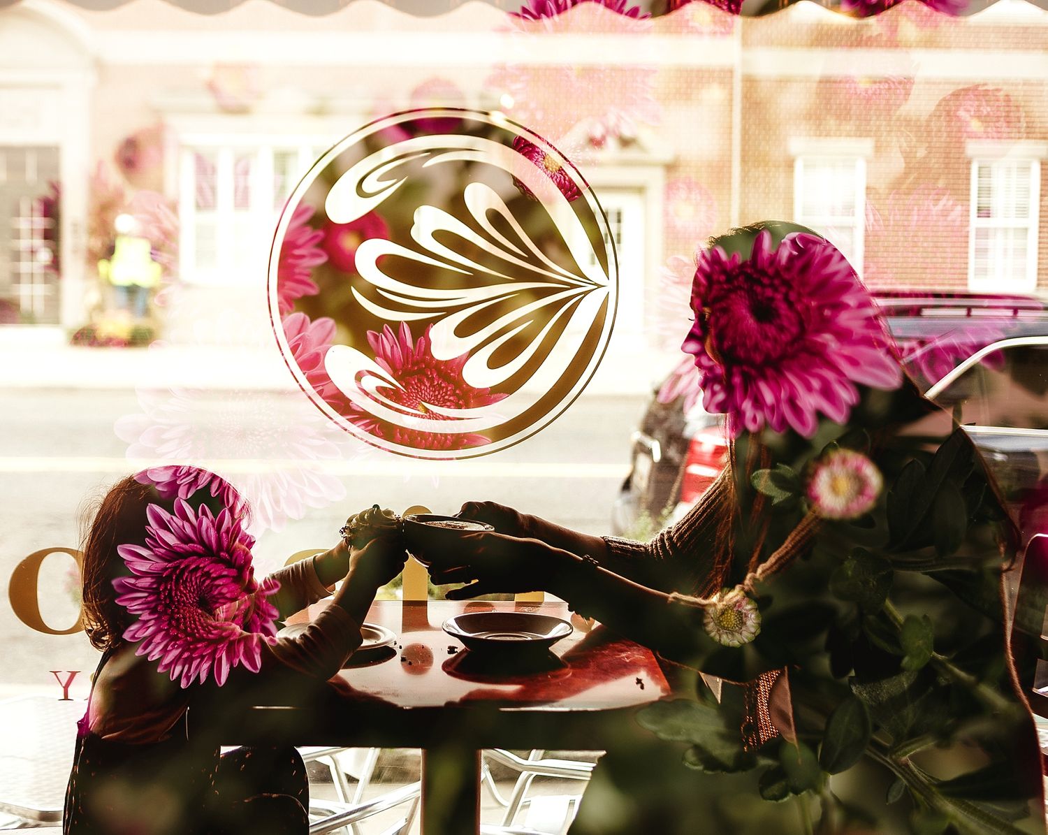 Artistic coffee latte art with pink gerbera daisies in cafe setting.
