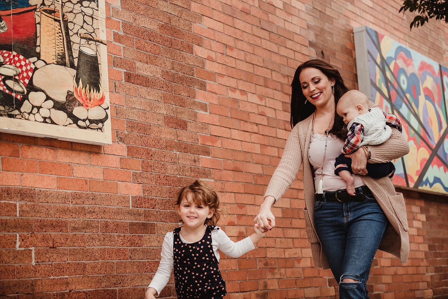 A joyful walk along a brick wall with graffiti art on a sunny urban street.
