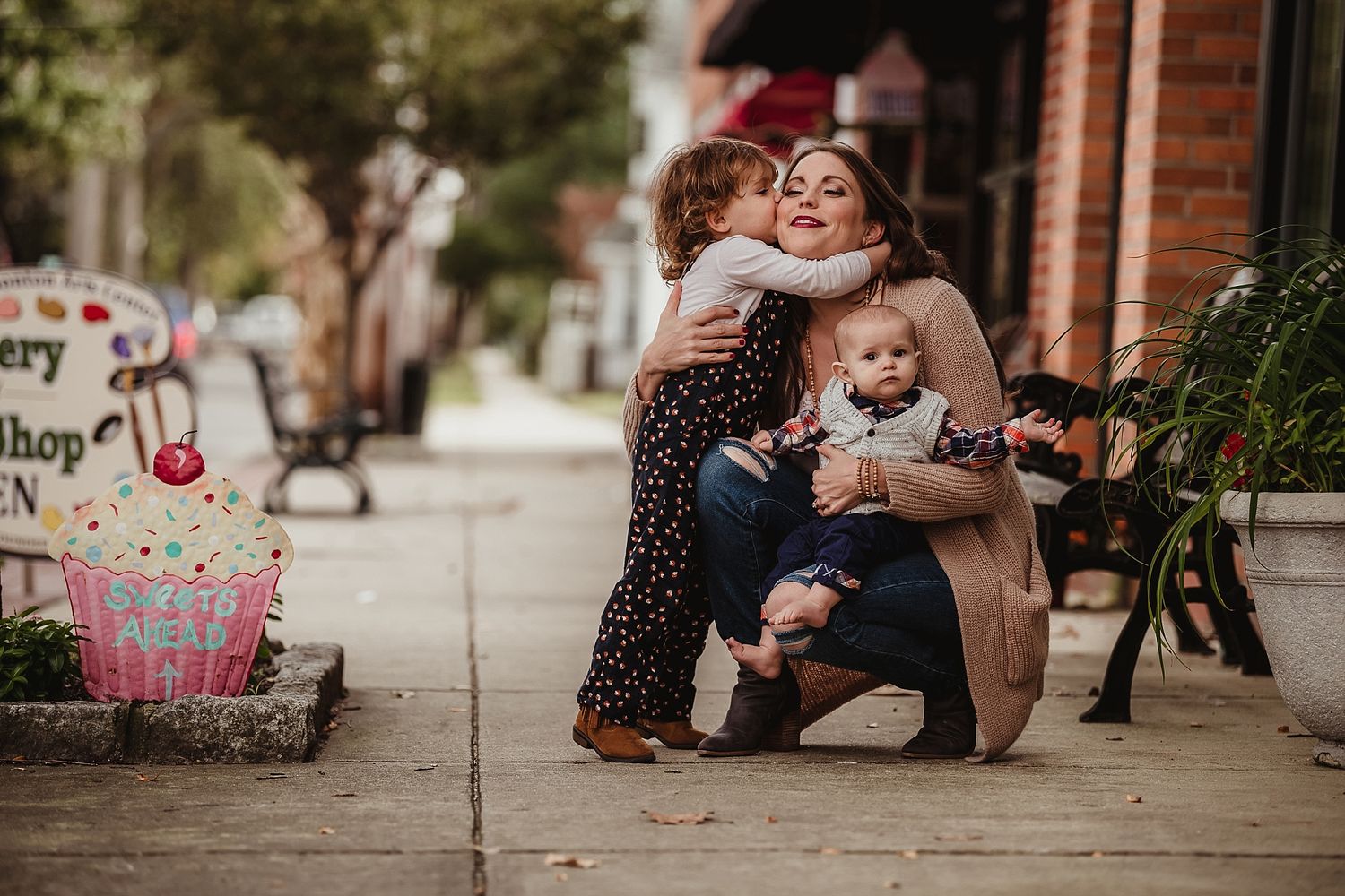 Family moment captured on sidewalk in front of brick building during autumn.