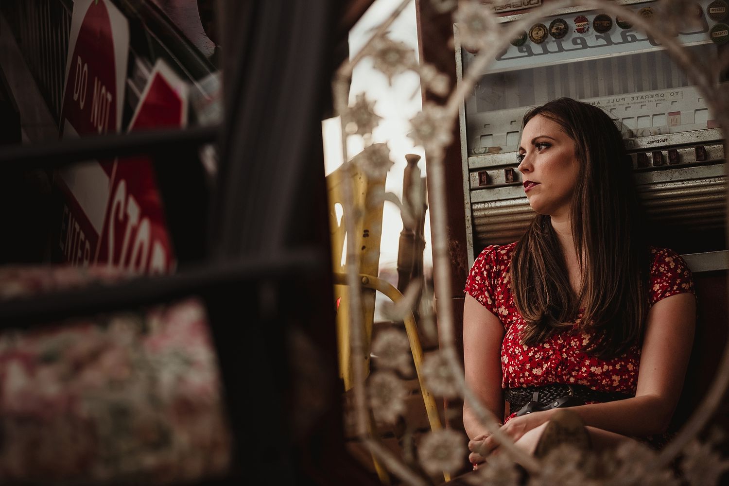 A moody portrait through vintage window panes with red dress and dramatic lighting.