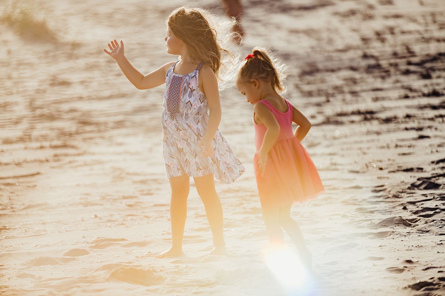Two silhouettes play in shallow water at sunset creating a magical scene.