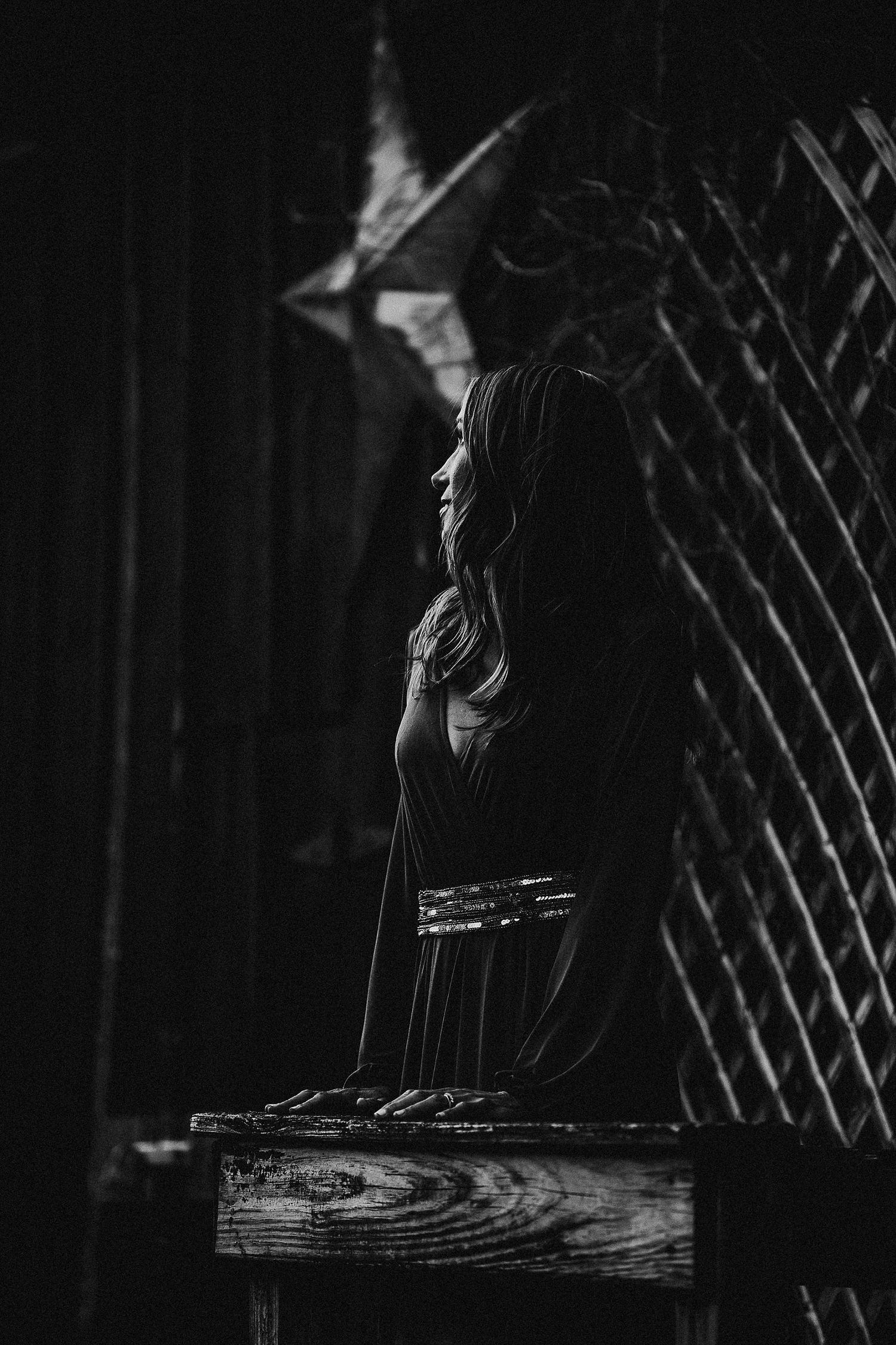Dramatic black and white portrait of person in profile against wooden lattice background.