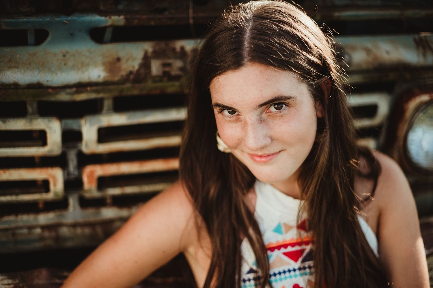 Portrait against rustic truck grill showing classic Americana style and warm lighting.