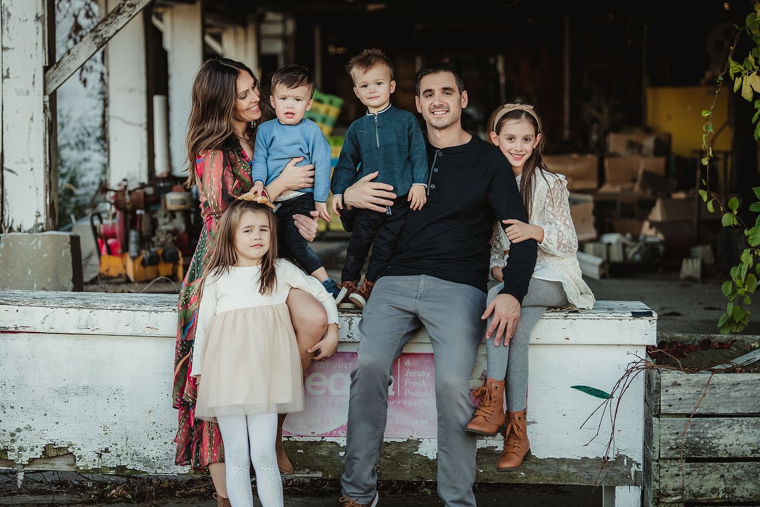 Casual family portrait taken outside rustic building with white siding.