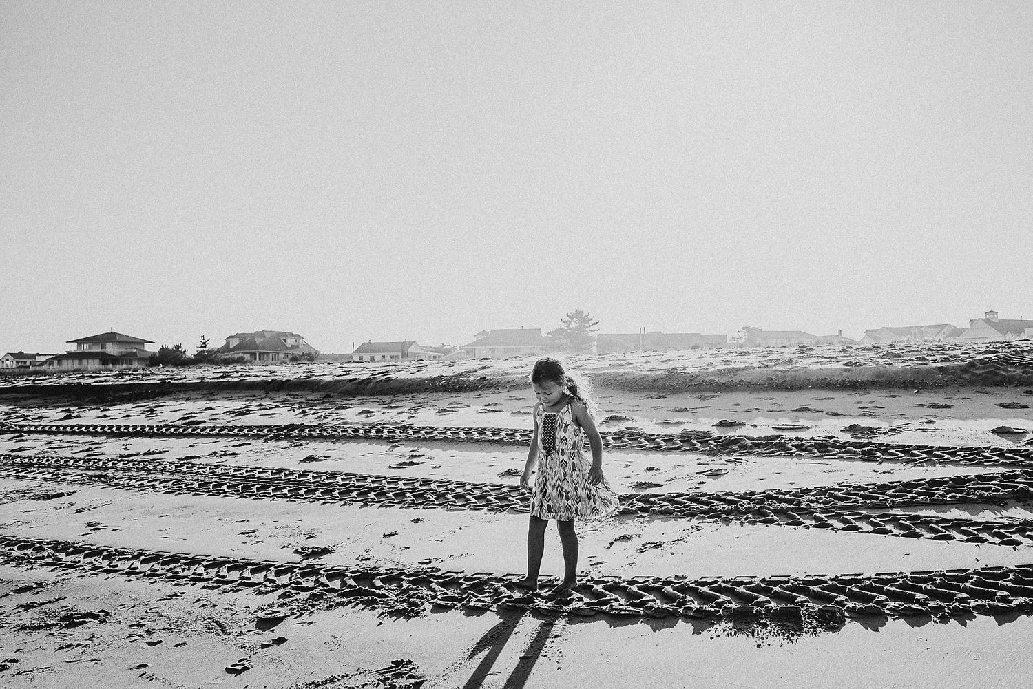 A person stands alone on a beach with geometric patterns drawn in the sand.