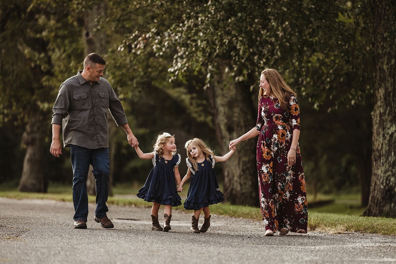 Family walking together on a path with young twins in matching navy dresses.