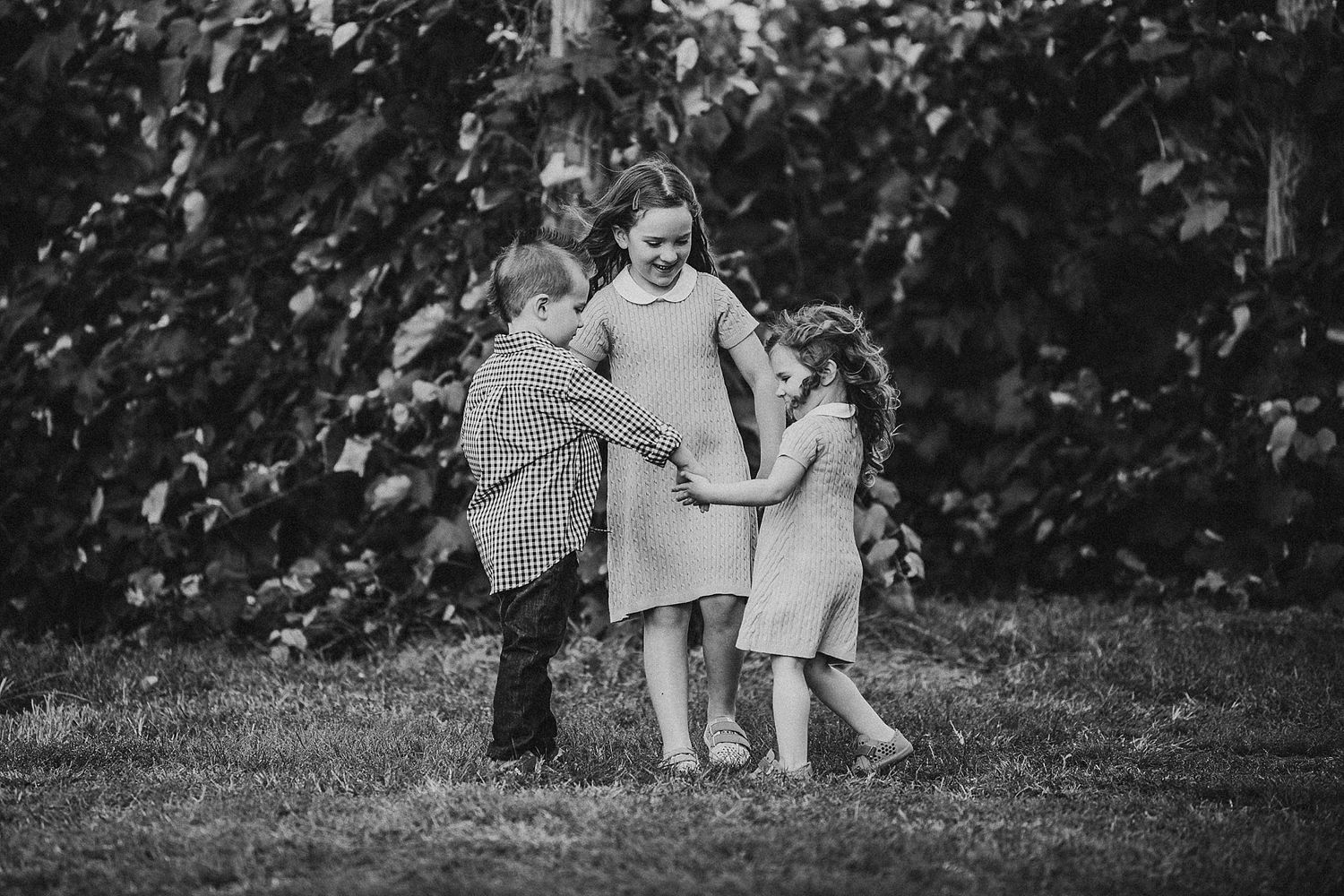 Children huddled together in an intimate black and white outdoor portrait.