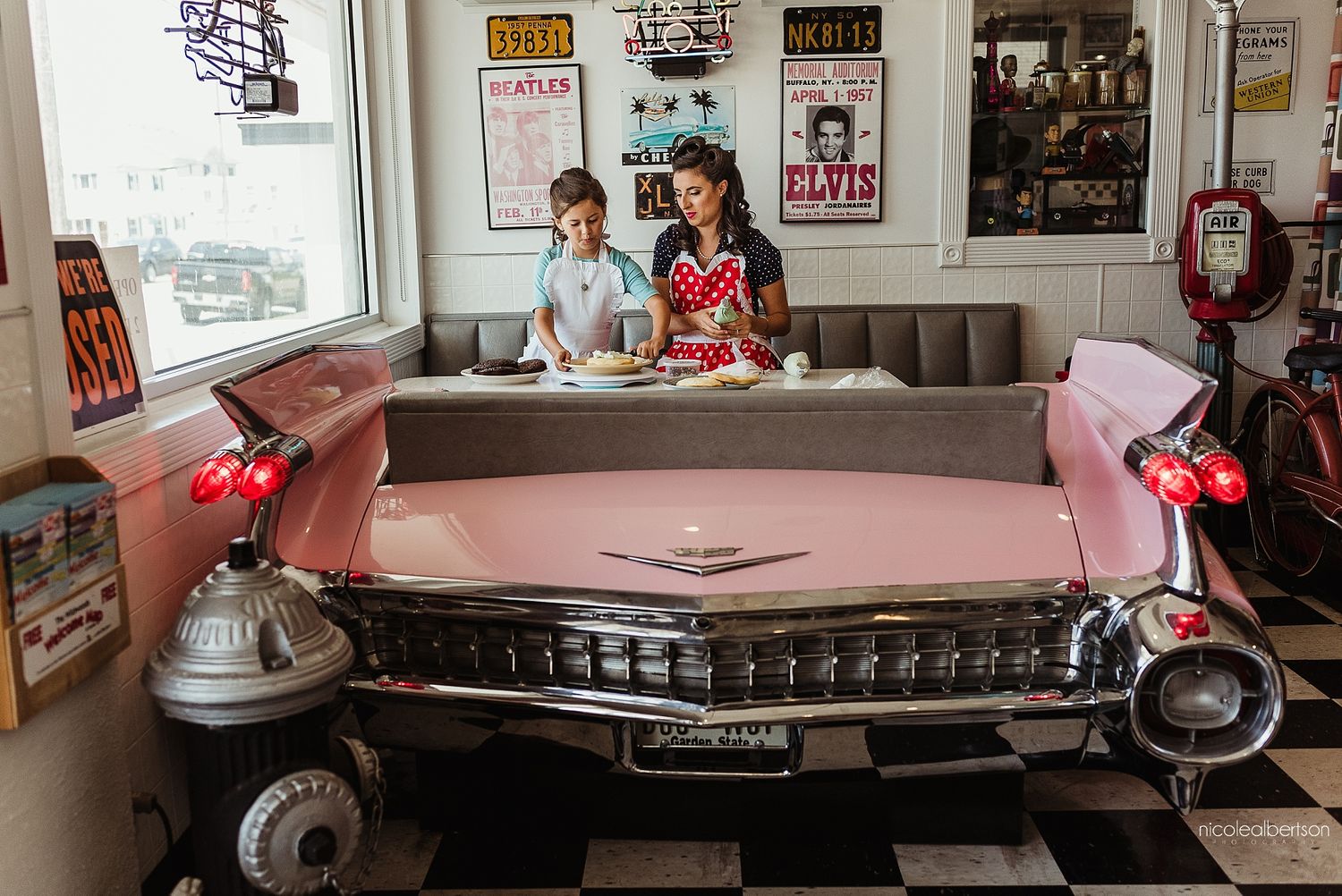 Retro-styled diner interior with classic pink Cadillac booth seating and vintage decorations.