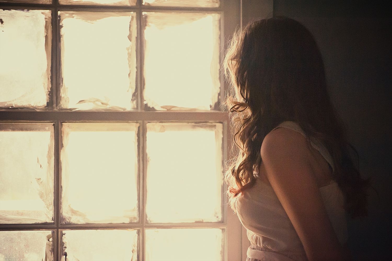 A silhouetted figure stands by a sunlit window in a romantic atmospheric setting.