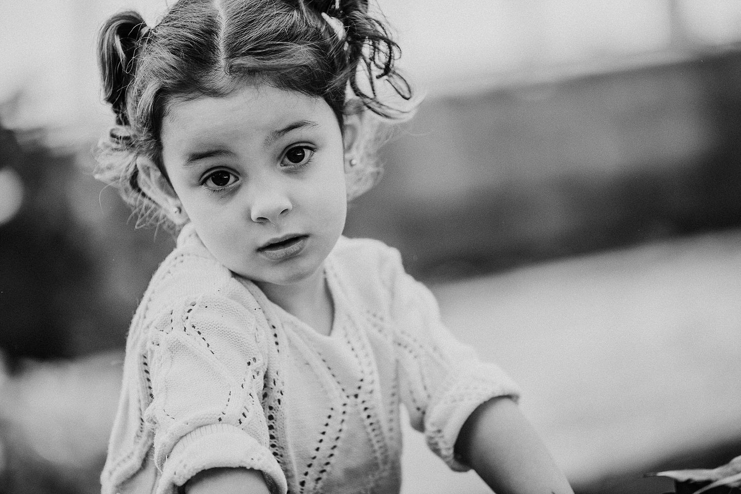 A close-up black and white portrait of a young child with curly hair.