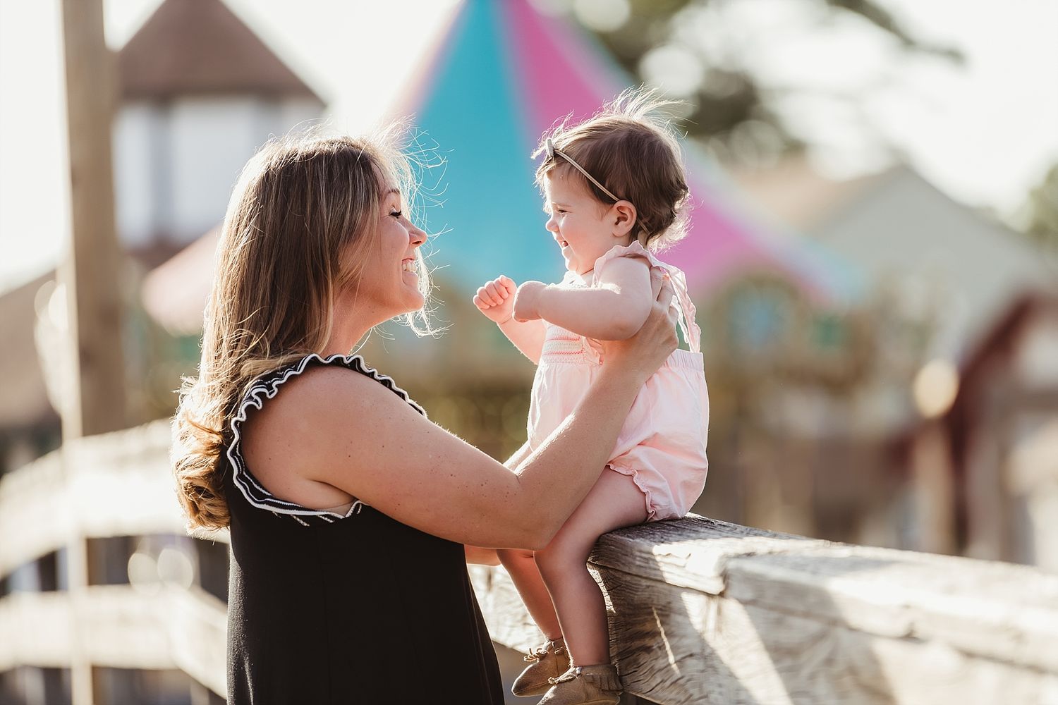 Sweet family moment at a carnival with colorful structures in the background.