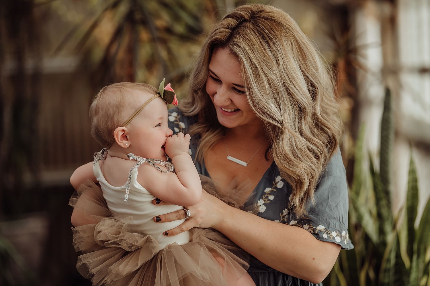 Intimate moment between mother and baby against a background of indoor plants.
