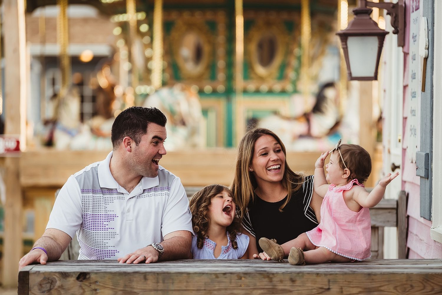 A happy family moment at a carnival with carousel lights in the background.