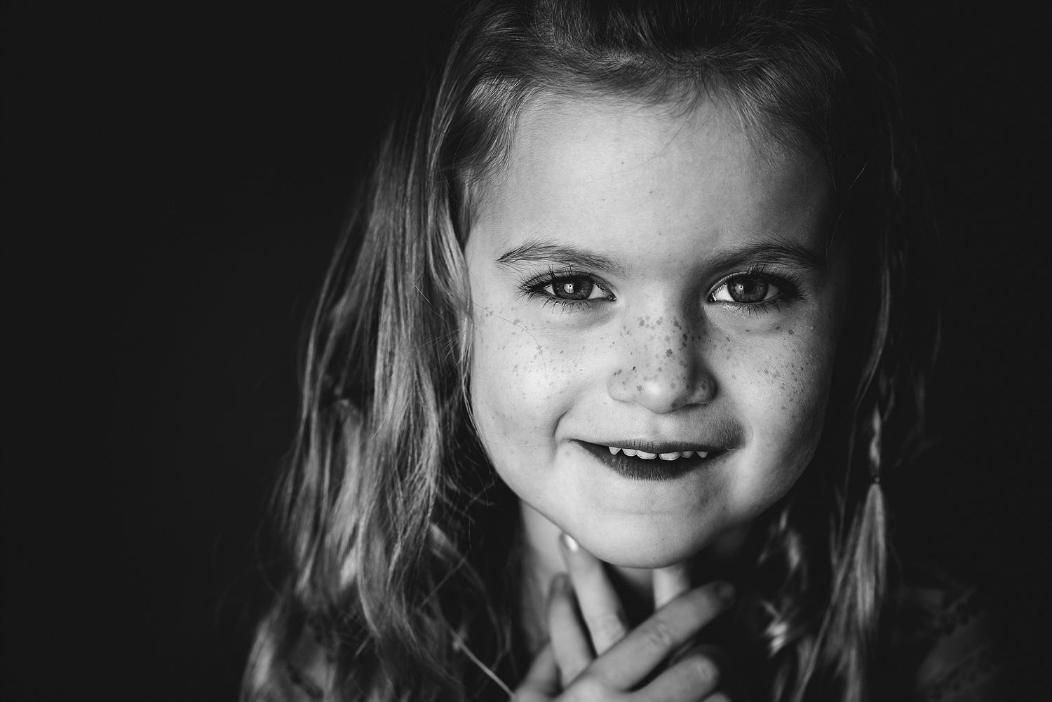 A dramatic black and white portrait with soft lighting on dark background.