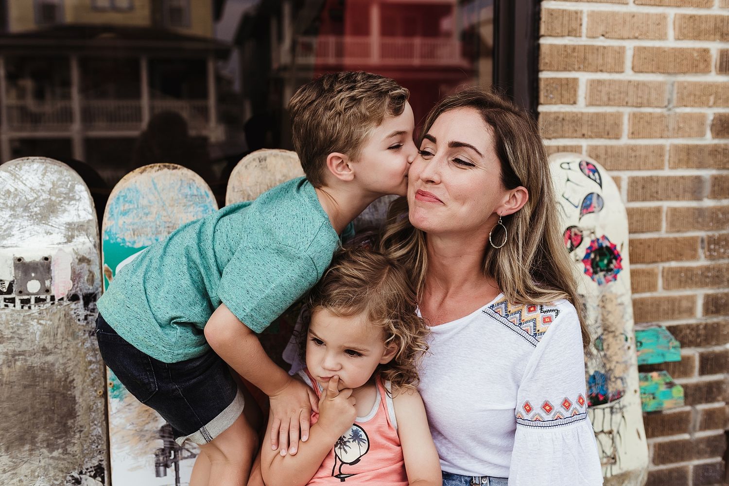 Candid family moment with skateboard collection displayed against brick wall.