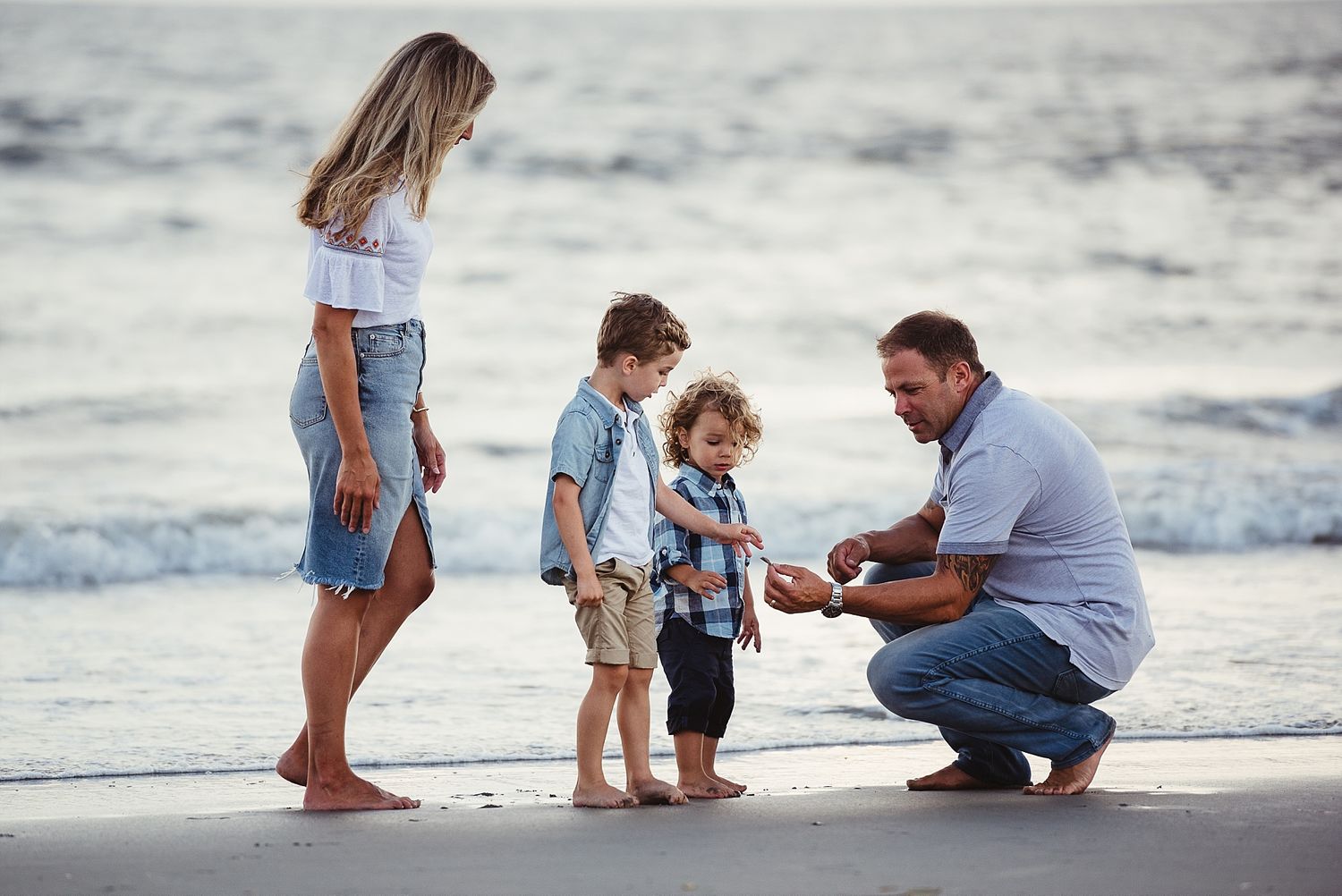 A family enjoys quality time together on a sandy beach near the ocean waves.