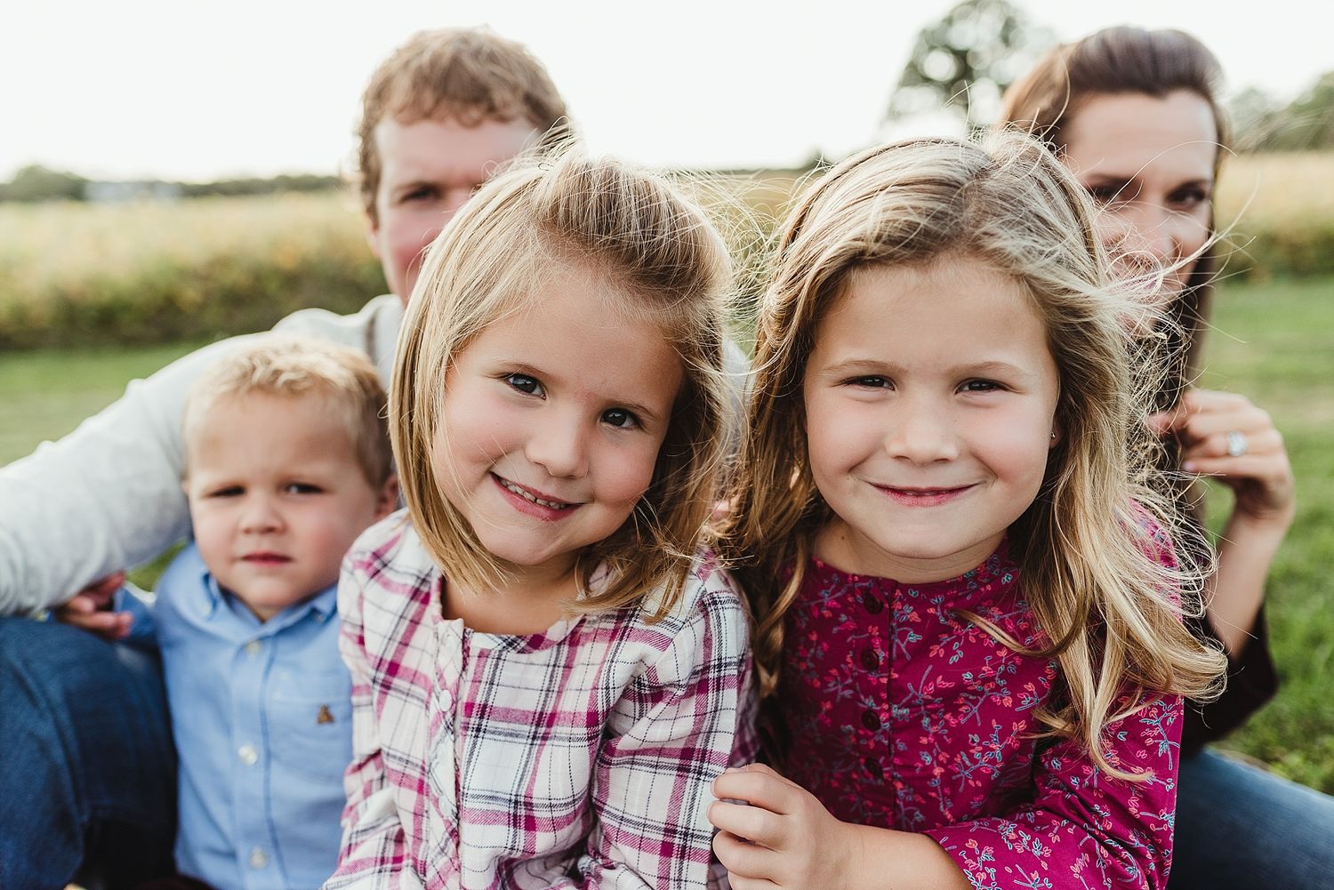 A group poses together for a close-up outdoor portrait in a grassy field.
