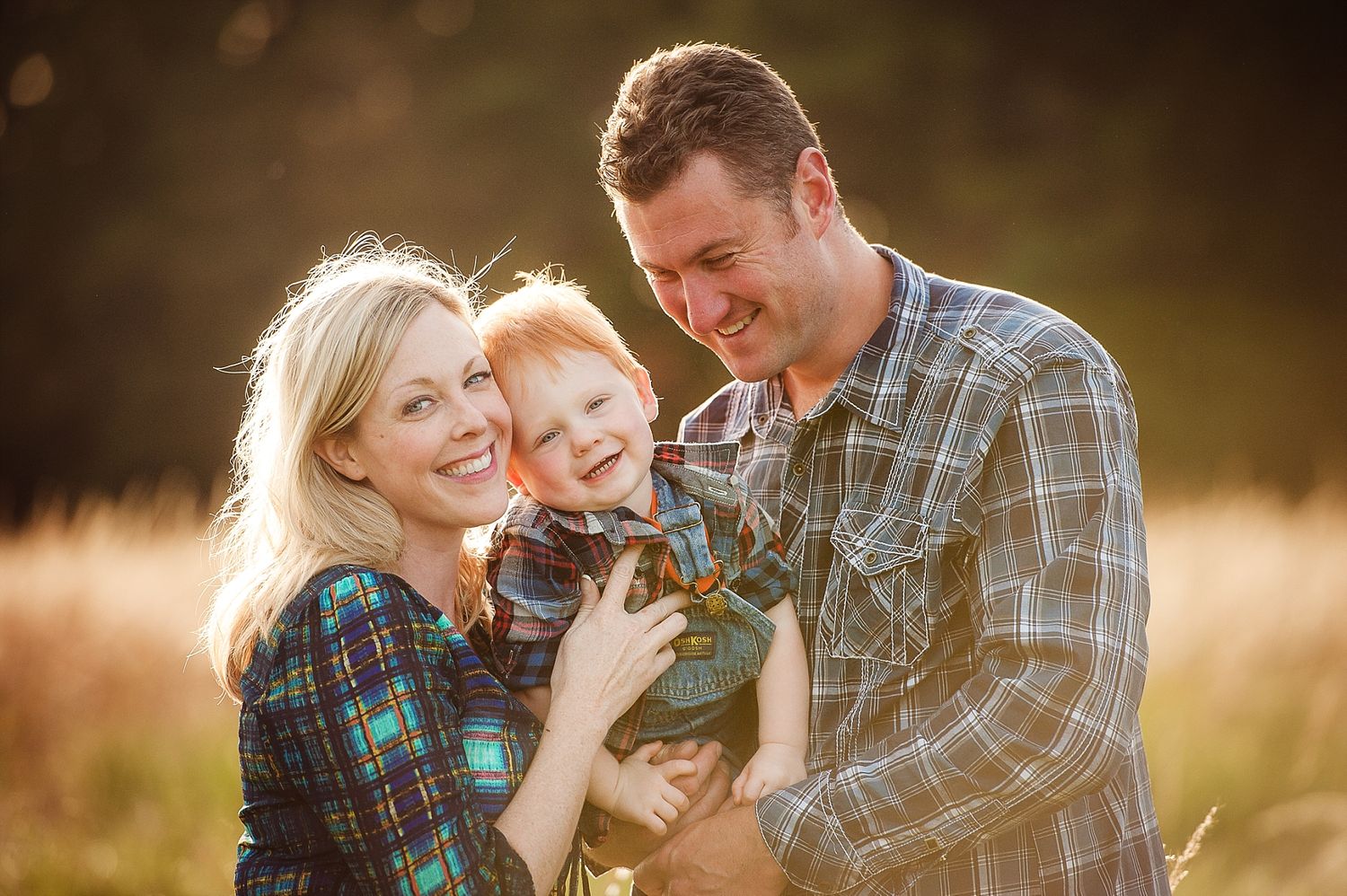 Family embracing and laughing together in golden sunset light.
