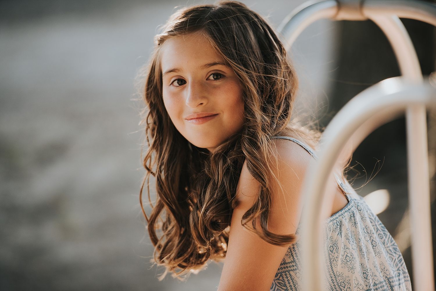 Portrait of someone with long brown hair sitting outdoors in natural light.