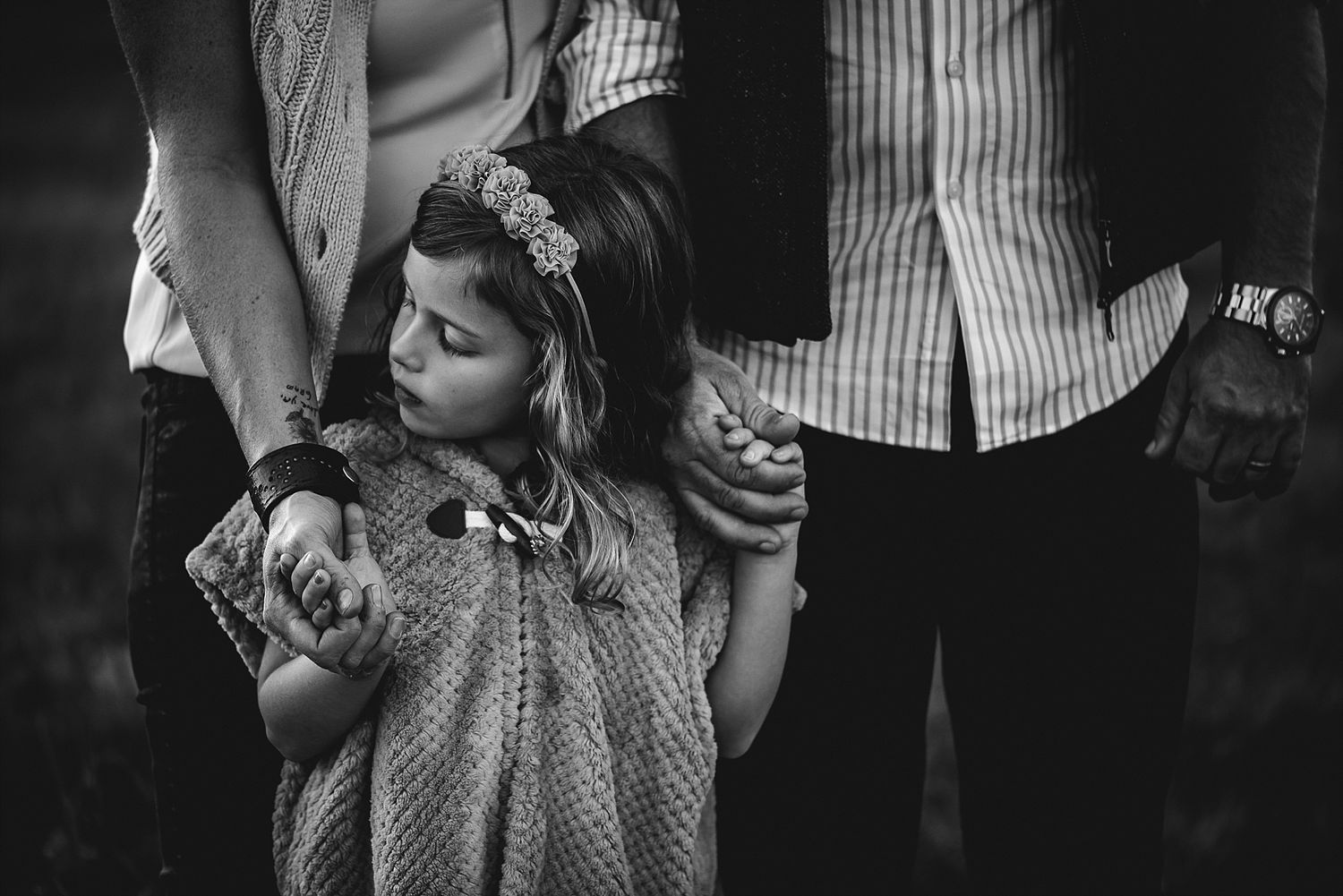 Black and white image of someone holding a rabbit while standing between adults.
