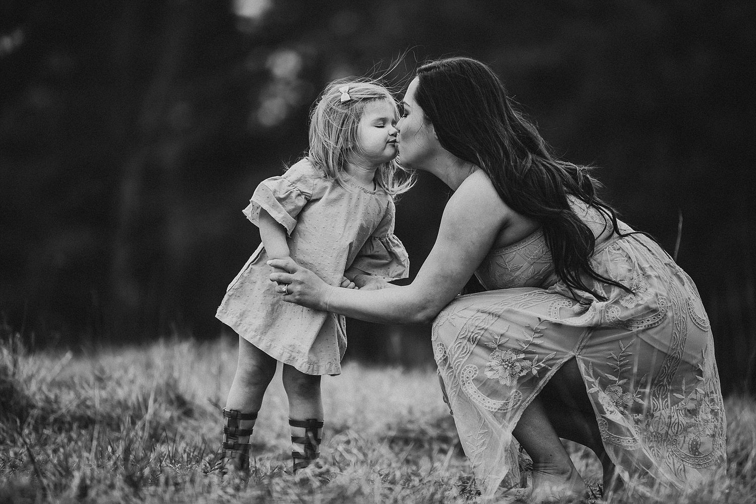 Black and white image of two people sharing a tender moment in a grassy field.