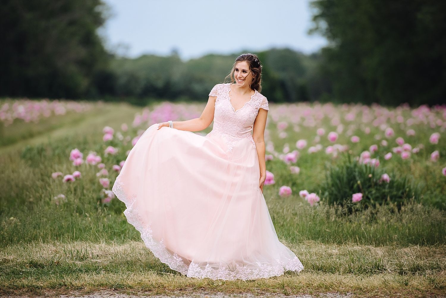 A flowing pink wedding dress twirls in a field of wildflowers.