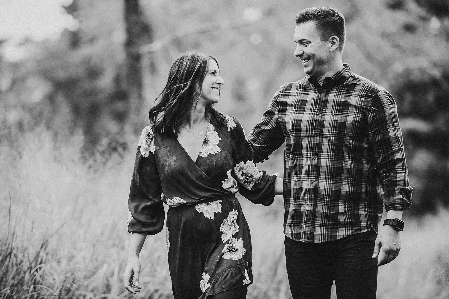 A black and white photo of a couple laughing together in a natural outdoor setting.