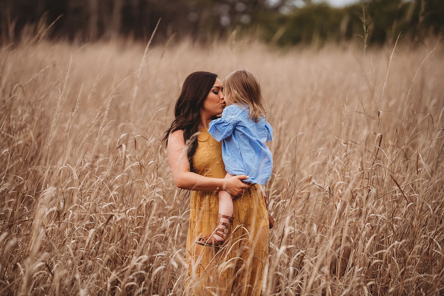 Tender moment captured in tall golden wheat field during sunset.