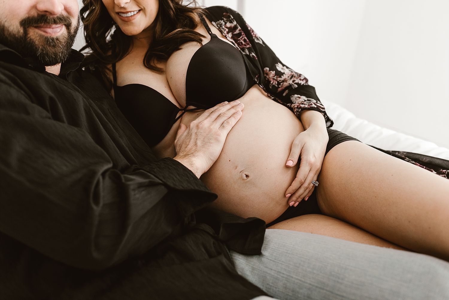 Intimate maternity photo showing pregnant belly with black lace lingerie.