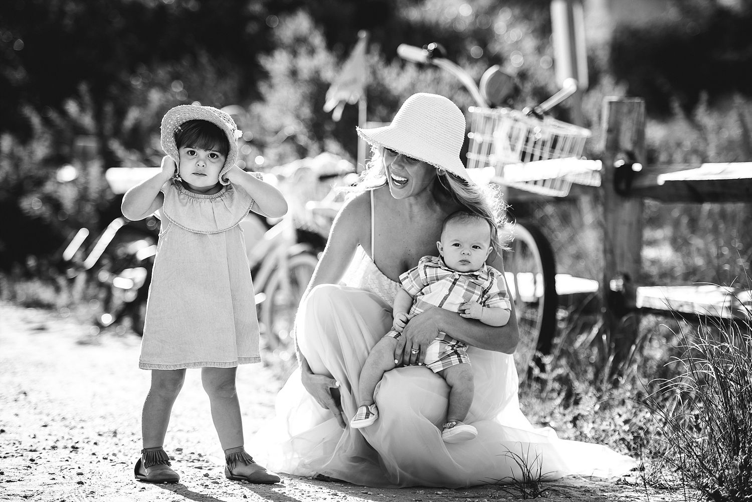A black and white photo capturing a tender outdoor moment with children on a sunny day.