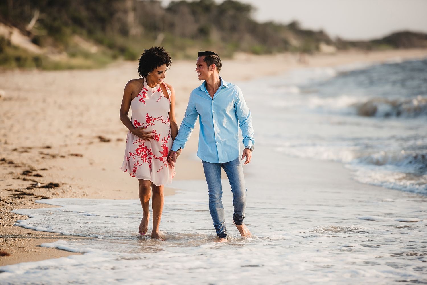 Couple walking together along a beautiful beach at sunset.