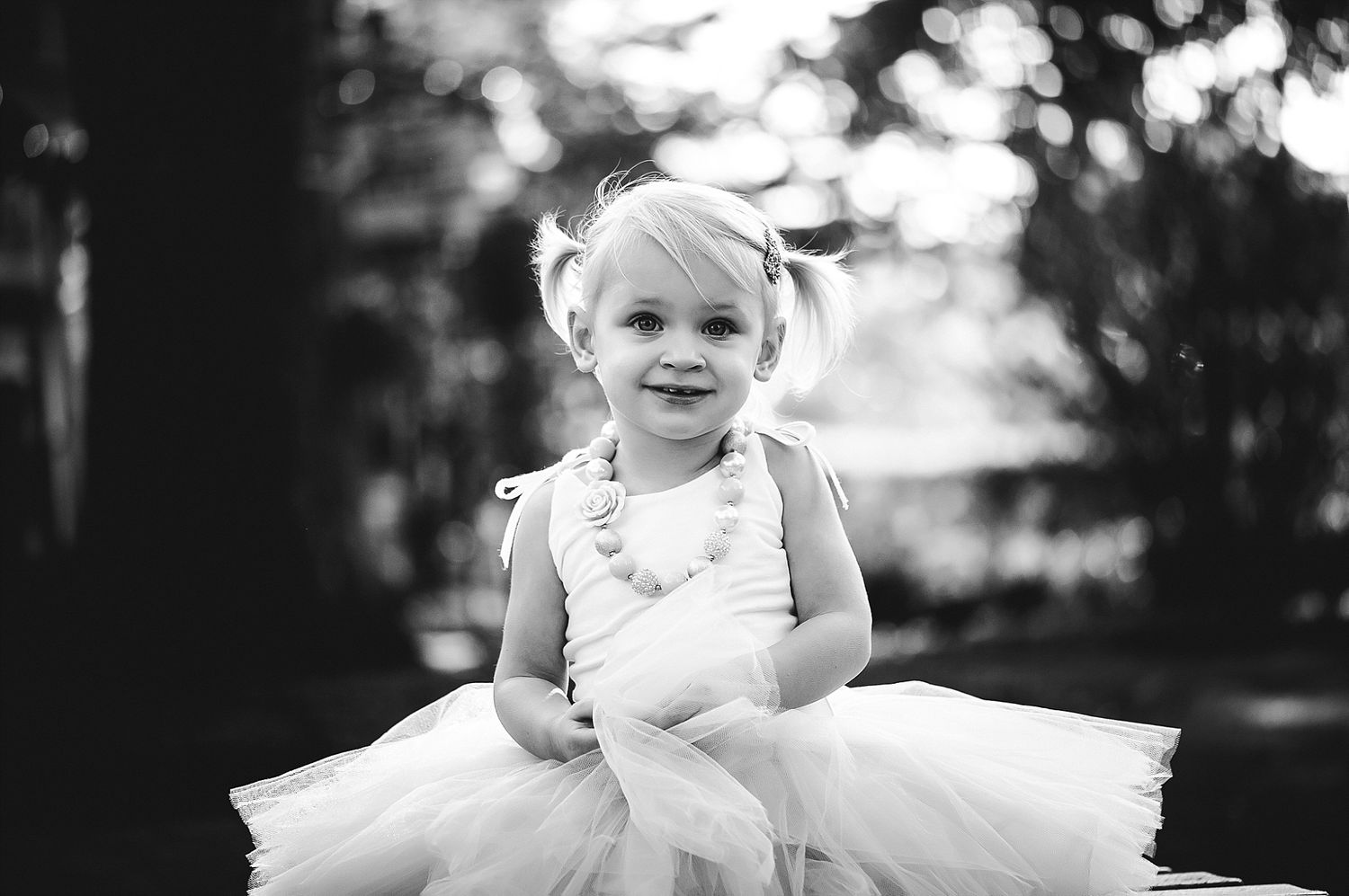 Black and white portrait of a small child in a tulle dress.