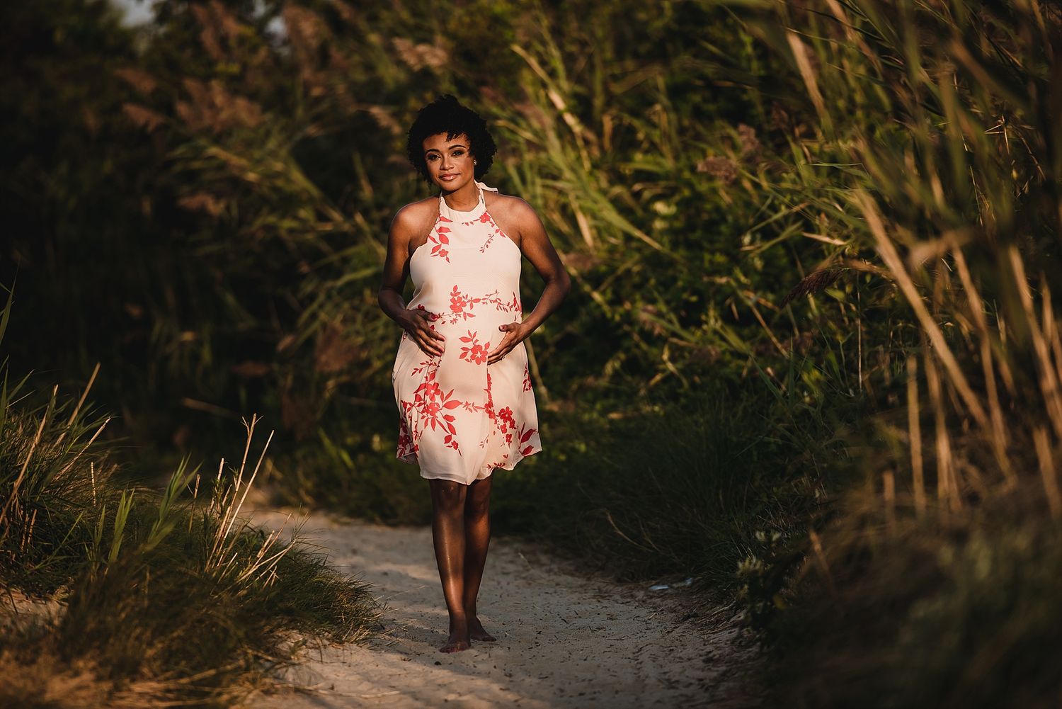 Woman in floral dress walking along nature path at golden hour.