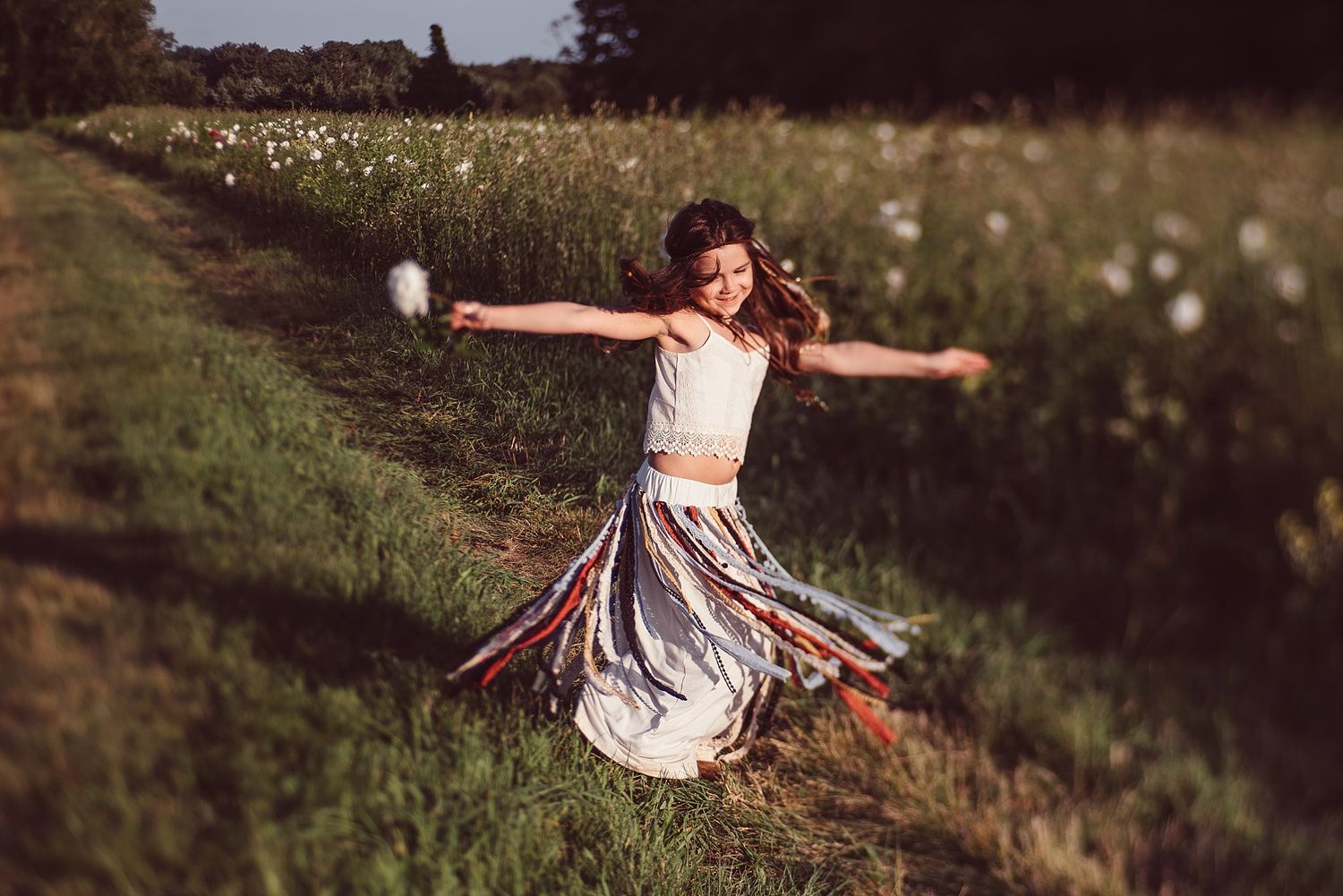 Young dancer twirling in a field of wildflowers at sunset.