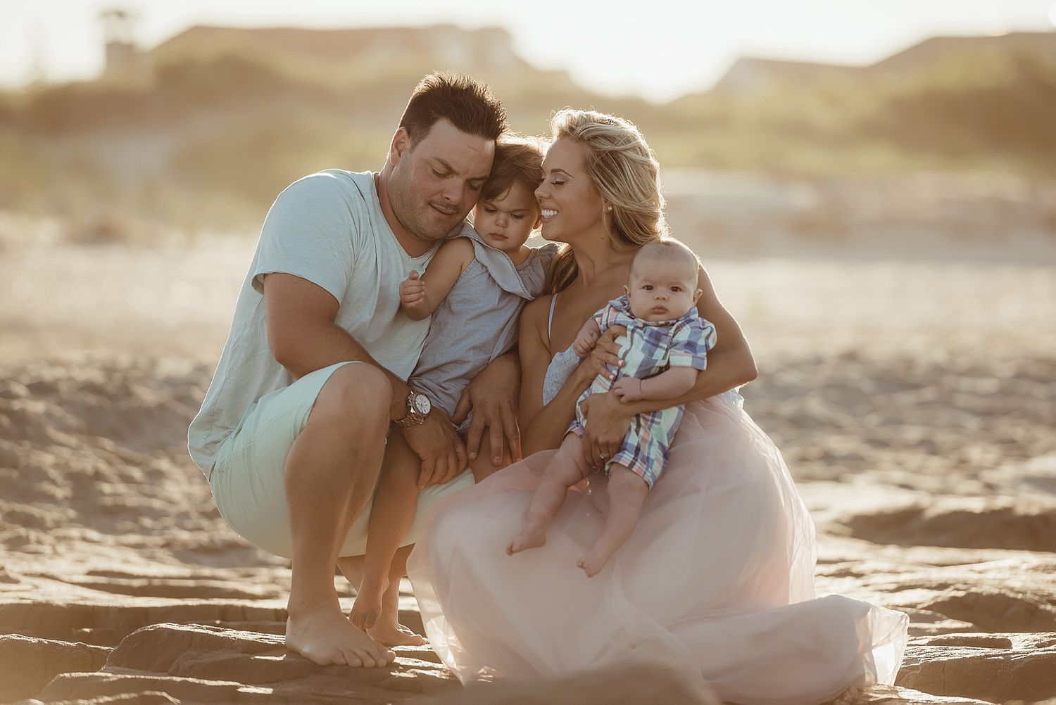 Family moment captured on beach during golden hour sunset.