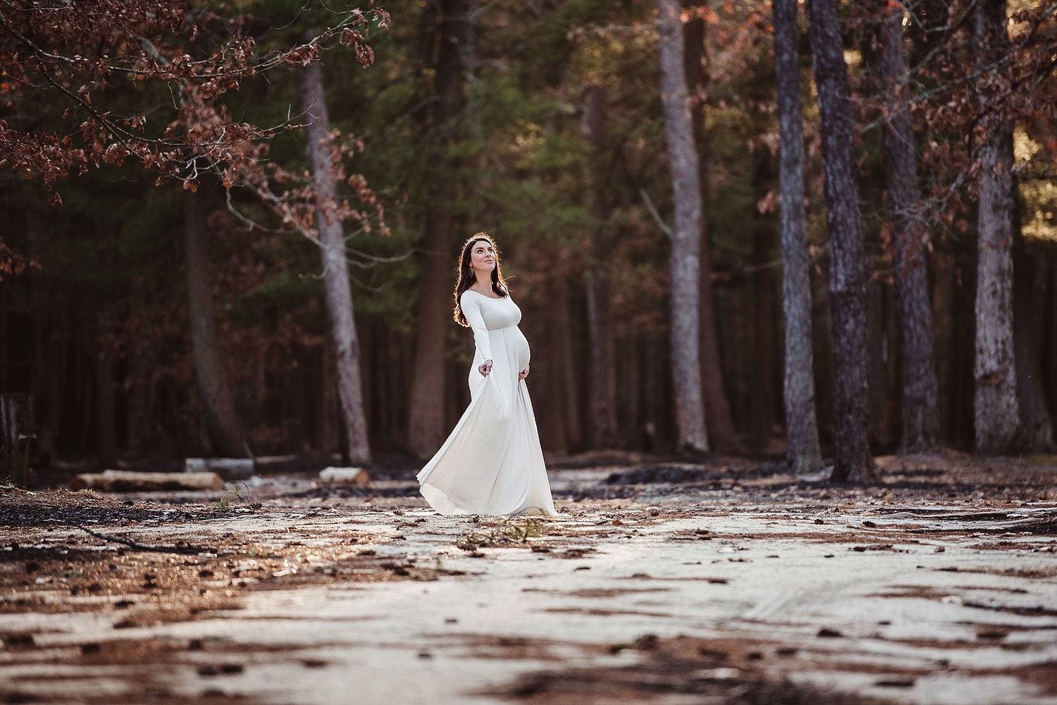 Person in white dress stands alone in snowy winter forest.