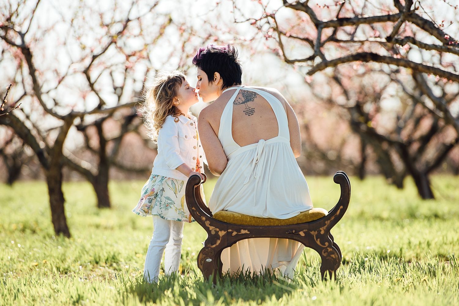 Children playing near antique bench in blooming spring orchard.