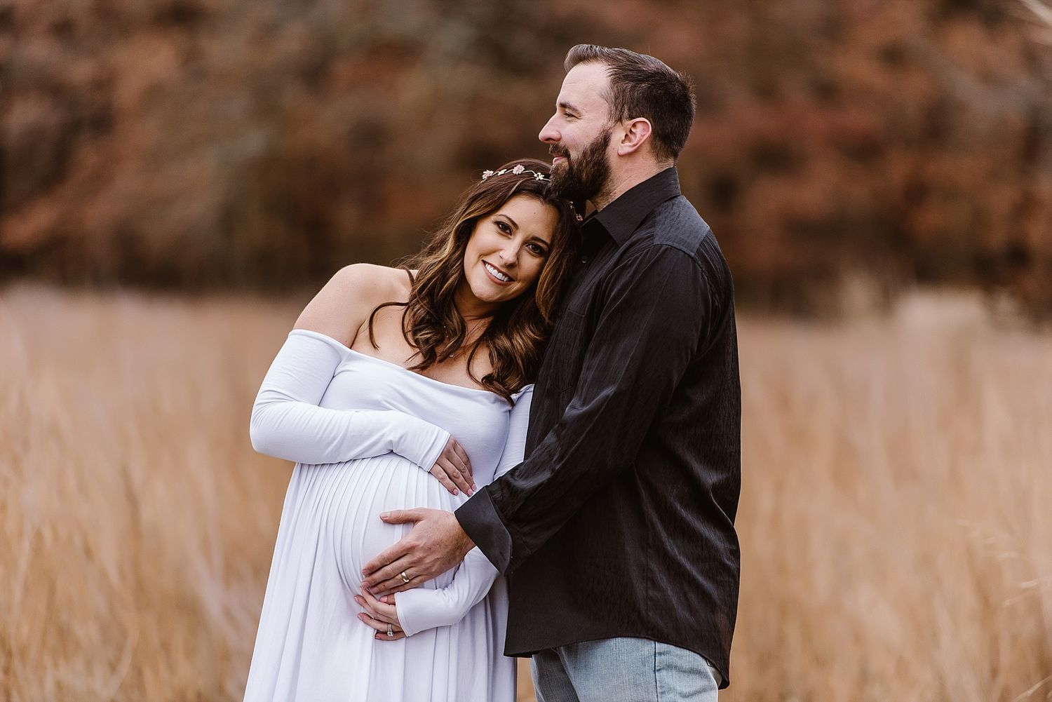 Maternity photo in autumn field with couple in casual attire.
