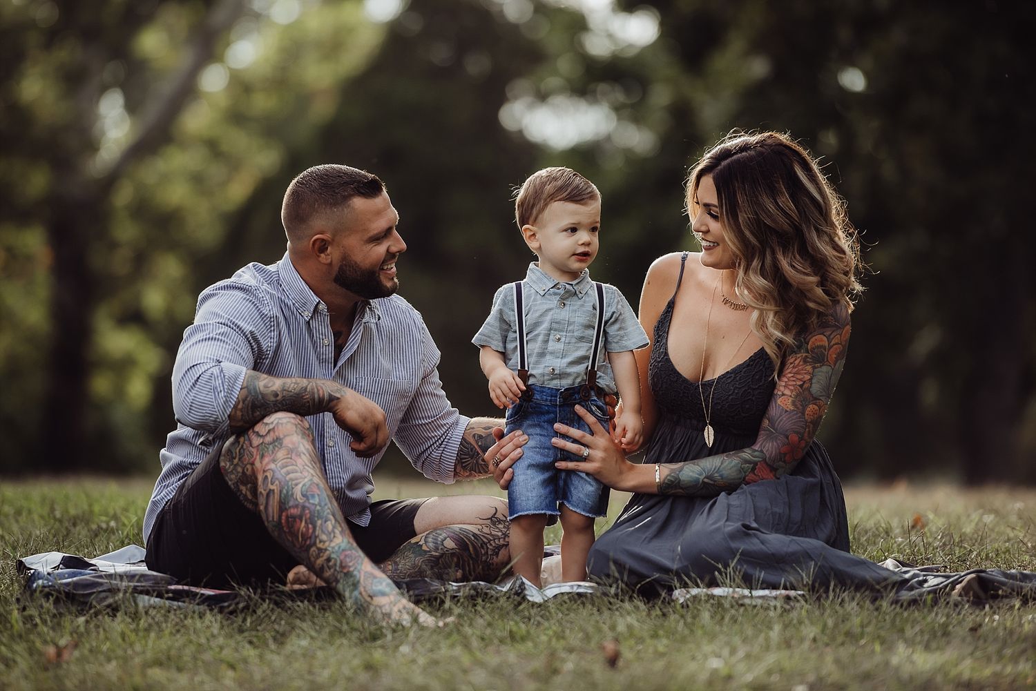 A family enjoys a relaxing picnic together on a grassy lawn in a park.