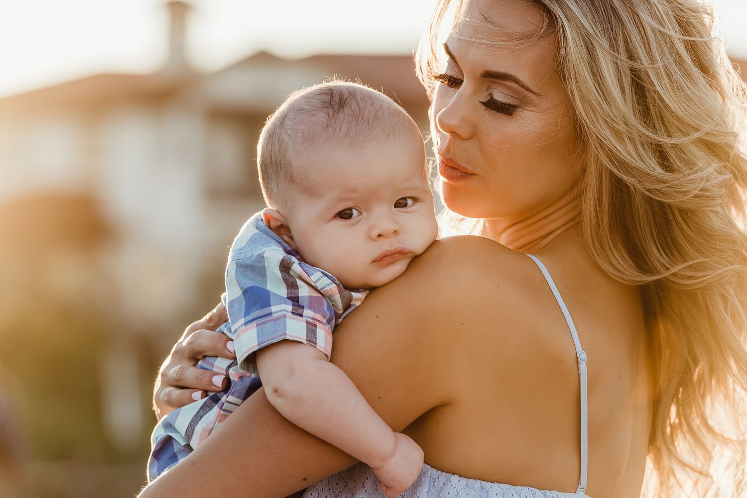 A tender moment between parent and baby during golden hour outdoors.
